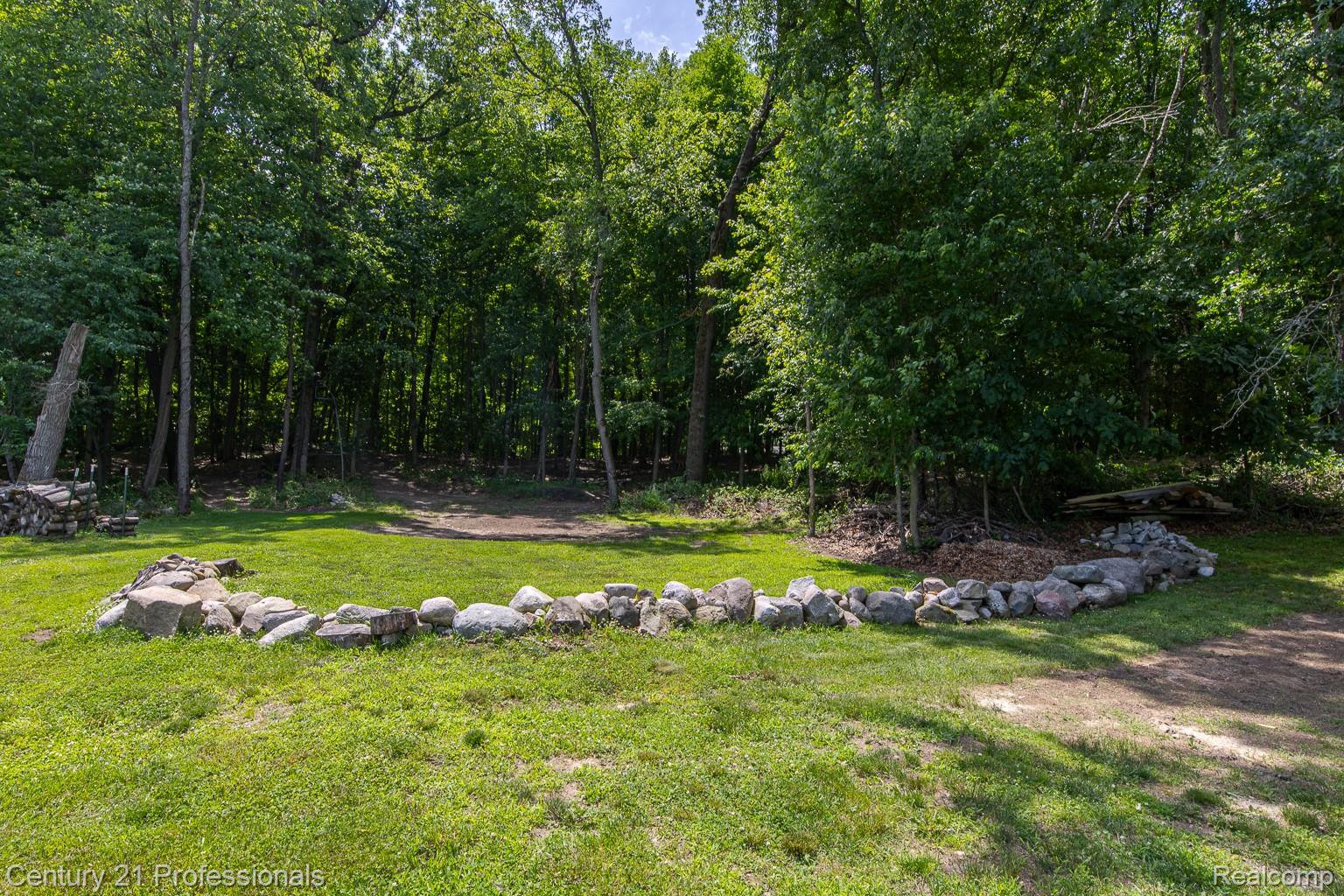 1790 Kent Road Ortonville, MI 48462 - Photo 51 of 64 Expansive grassy area featuring a natural stone border and a dense treeline backdrop