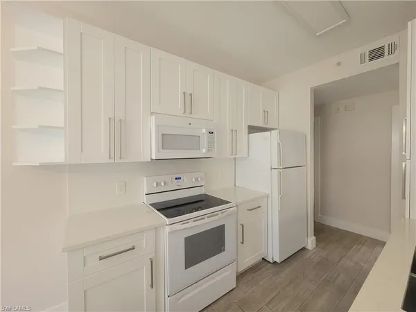 a kitchen with white cabinets and white appliances