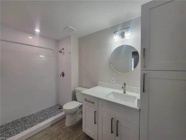 a bathroom with a toilet sink a mirror and vanity