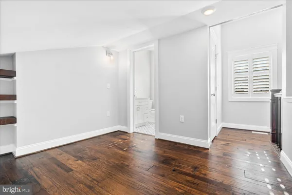 a view of an empty room with wooden floor and closet