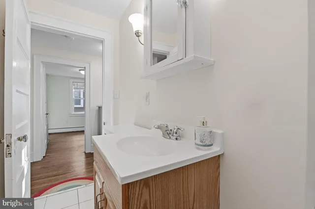 a view of a hallway to a livingroom with wooden floor and sink