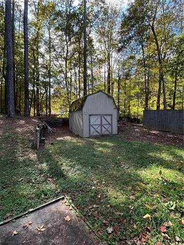 a view of a backyard with large trees and a barn