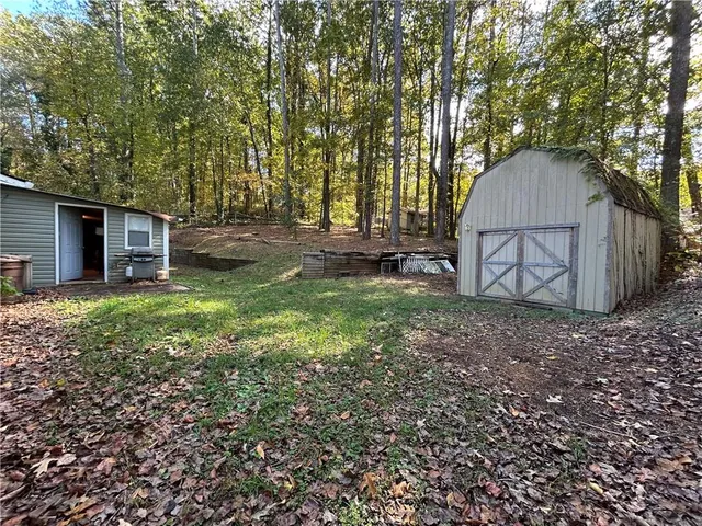 a view of a backyard with large trees and wooden fence