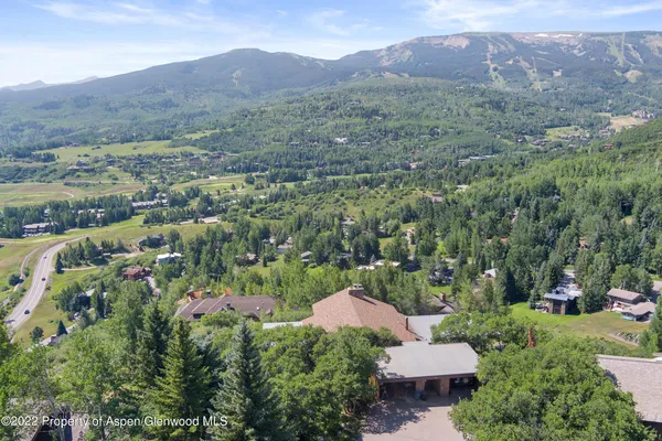 an aerial view of a house around side of green landscape