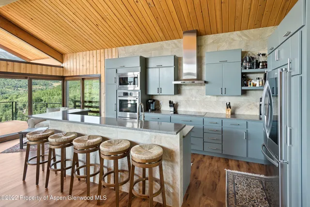 a kitchen with stainless steel appliances granite countertop table chairs and a large window