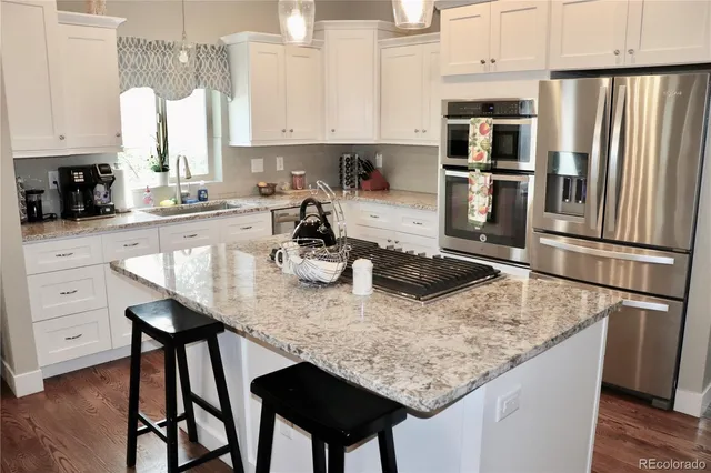 a kitchen with stainless steel appliances granite countertop a table chairs stove and refrigerator