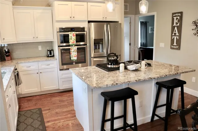 a kitchen with stainless steel appliances kitchen island granite countertop a table chairs sink and cabinets