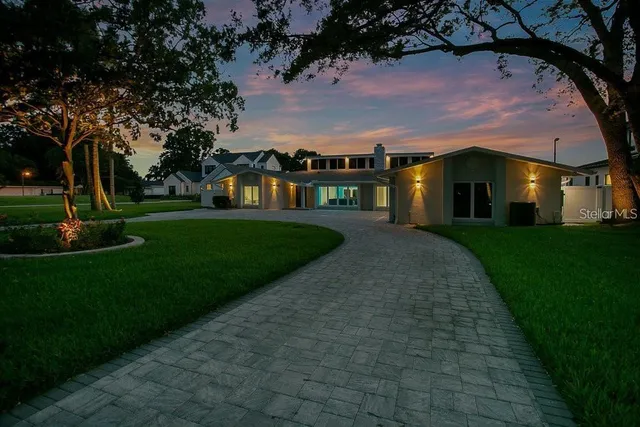 a view of house in front of a big yard with large trees
