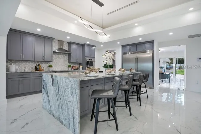 a kitchen with stainless steel appliances granite countertop a table chairs sink refrigerator and cabinets