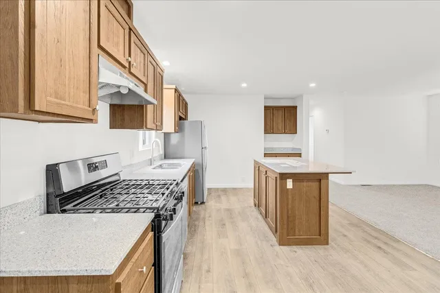 a kitchen with stainless steel appliances granite countertop a sink and a refrigerator