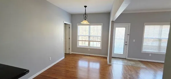 a hallway with wooden floor chandelier and a window