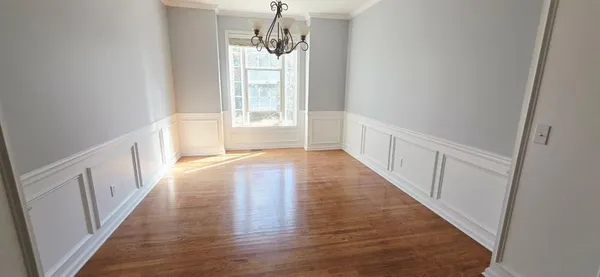 a view of a hallway with wooden floor and chandelier