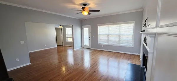 a view of an empty room with wooden floor and a window