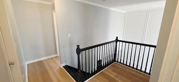 a view of a hallway with wooden floor and a bathroom
