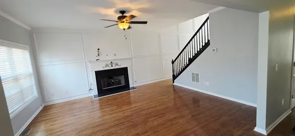 a view of an empty room with wooden floor and a window