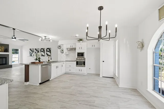 a kitchen with stainless steel appliances granite countertop a sink a stove top oven a chimney and a counter top space