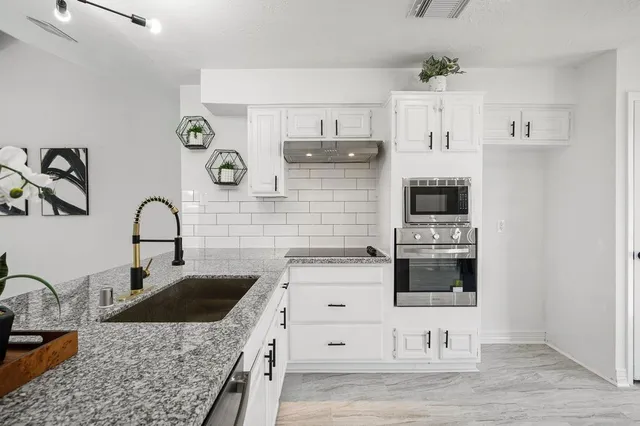 a kitchen with white cabinets and window