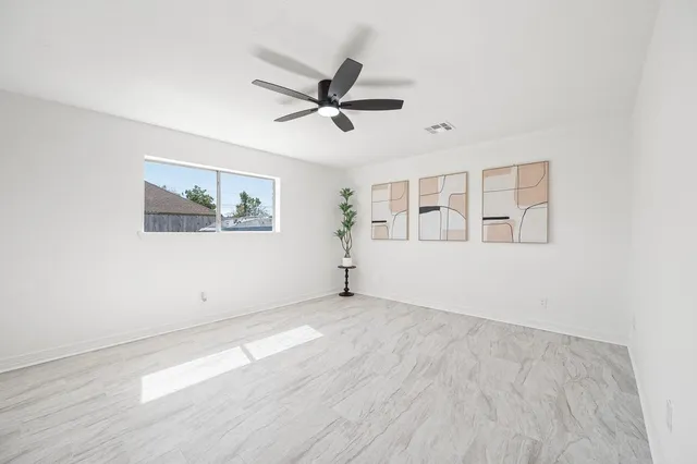 a view of a livingroom with a potted plant a ceiling fan and window