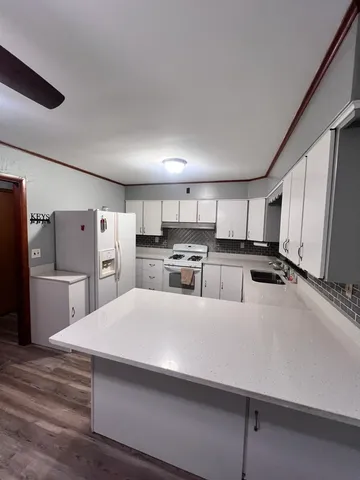 a large white kitchen with a refrigerator a stove and a sink
