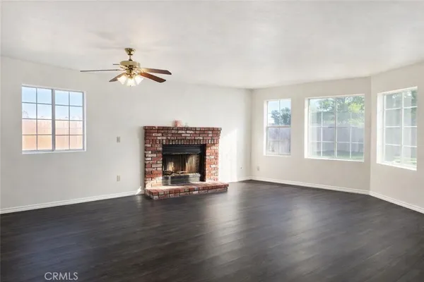 an empty room with windows fireplace and wooden floor