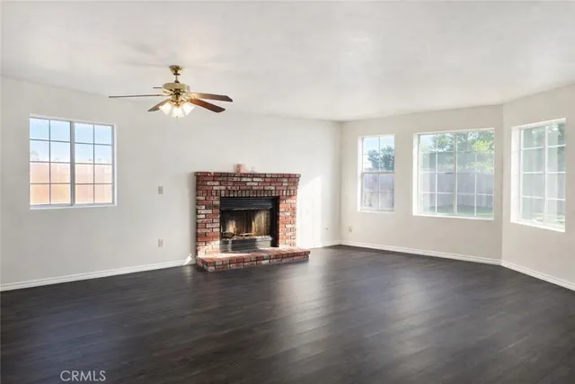 an empty room with windows fireplace and wooden floor