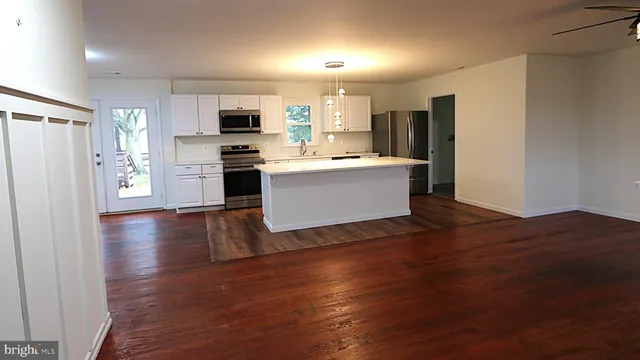 a view of kitchen with stainless steel appliances wooden floor and window