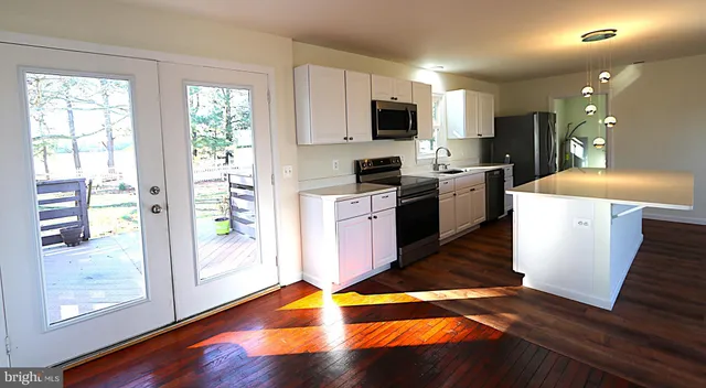 a kitchen with kitchen island wooden floors appliances and cabinets