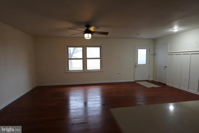 a view of an empty room with a window and wooden floor