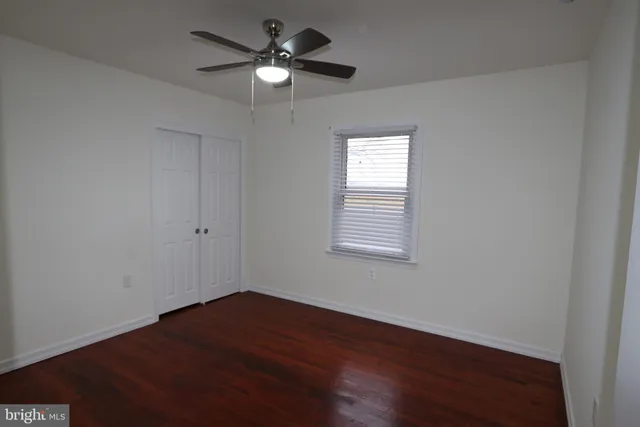 an empty room with wooden floor chandelier fan and windows