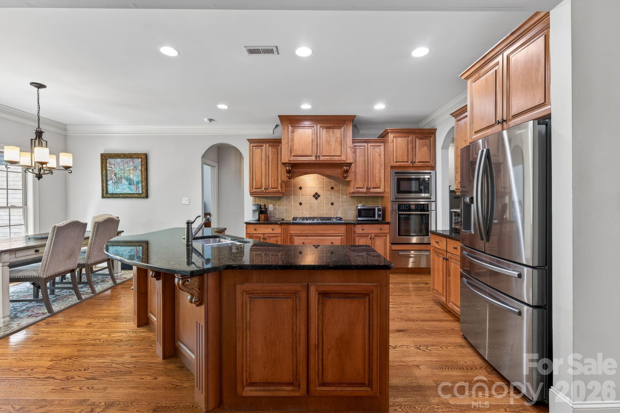 3138 Rappahannock Court, Unit 16 Matthews, NC 28104 - Photo 24 of 38 a kitchen with stainless steel appliances granite countertop a refrigerator a stove and a sink with wooden floor