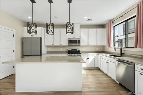 a kitchen with stainless steel appliances granite countertop a stove a sink dishwasher and a refrigerator with wooden floor