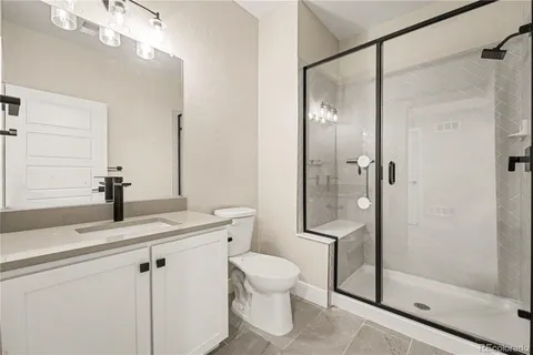 a bathroom with a shower sink vanity mirror and toilet