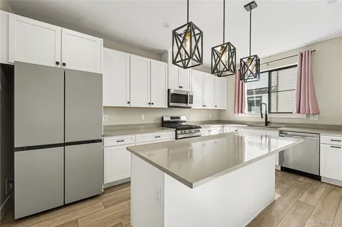 a kitchen with stainless steel appliances granite countertop a refrigerator a sink dishwasher a stove and a refrigerator