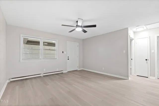 an empty room with wooden floor ceiling fan and window