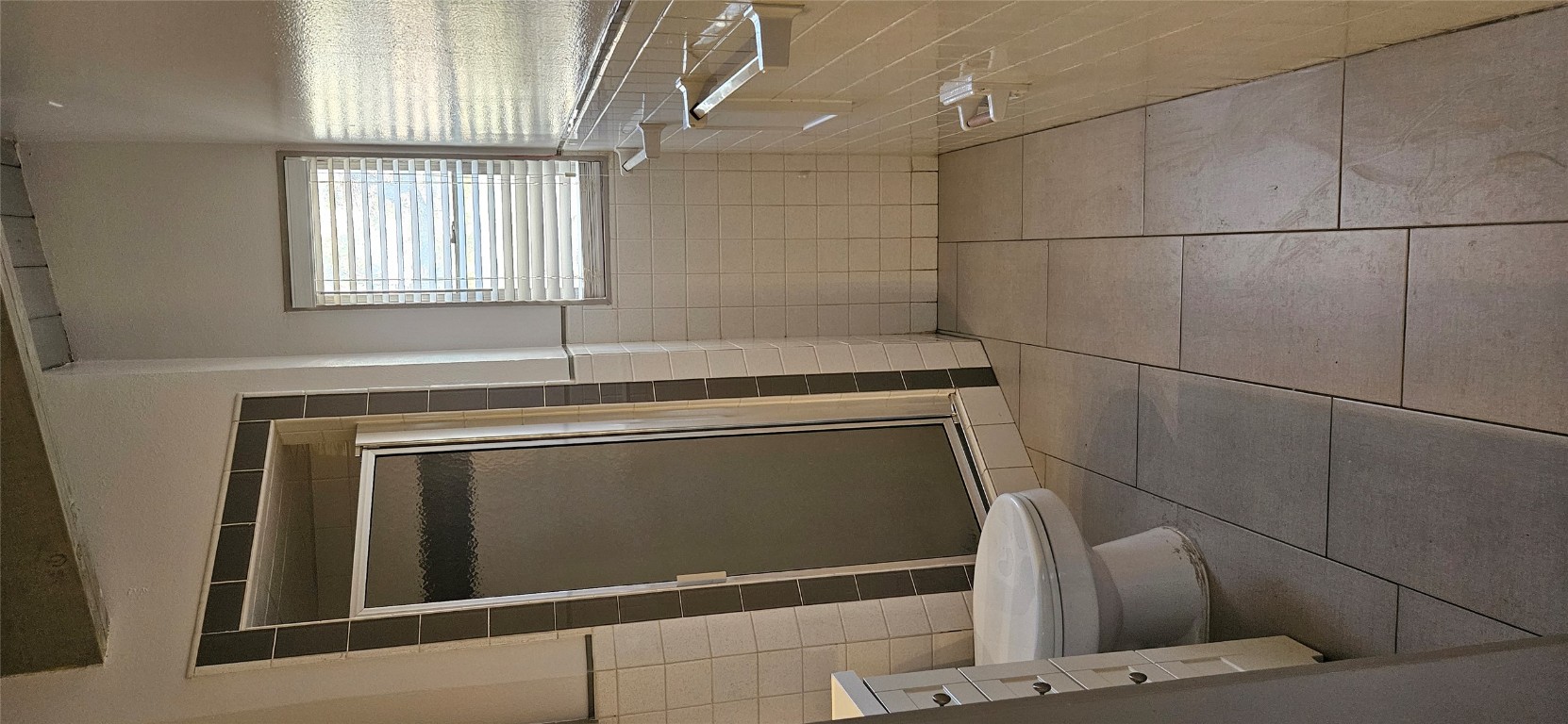 506 West 7th Street, Unit B Austin, TX 78701 - Photo 12 of 14 Bathroom featuring tile walls, a shower stall, light tile patterned flooring, wainscoting, and vanity