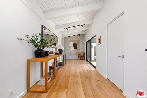 a view of a hallway with wooden floor and a potted plant