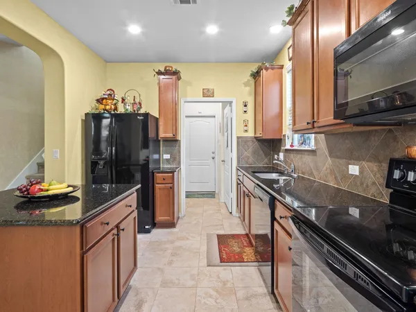 a kitchen with stainless steel appliances granite countertop a stove top oven a sink a dining table and chairs with wooden floor