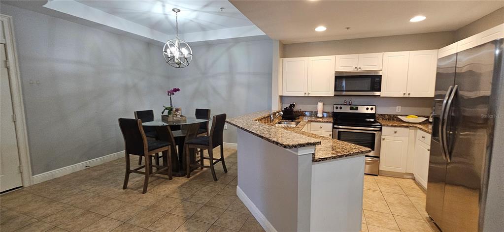 1502 Southwest 50th Street, Unit 104 Cape Coral, FL 33914 - Photo 4 of 18 a kitchen with kitchen island granite countertop a sink appliances and cabinets