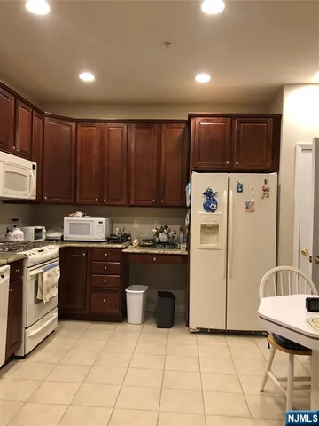 a kitchen with a refrigerator a stove top oven and cabinets