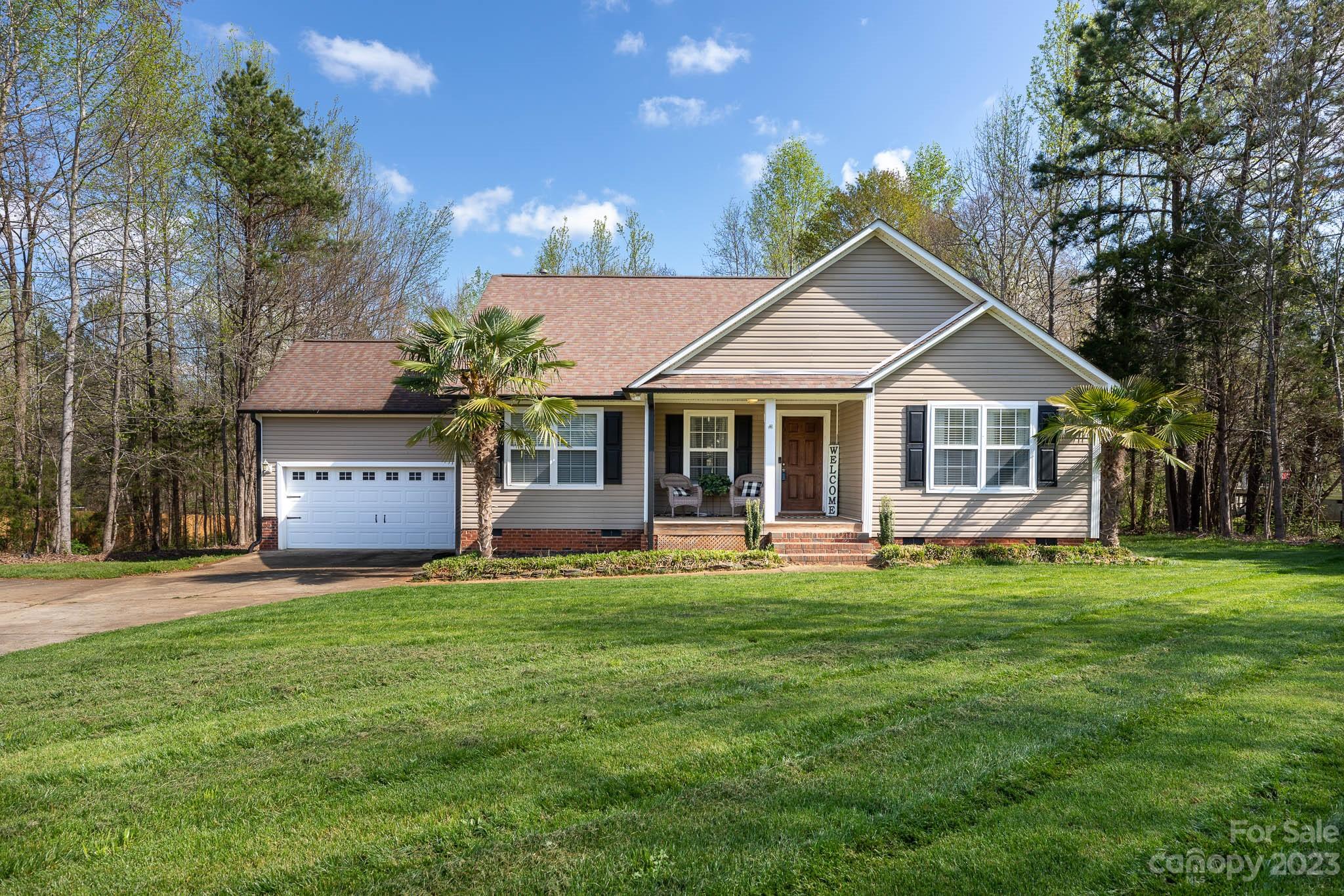 a front view of a house with a garden and trees