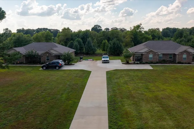 a aerial view of a house next to a yard and big trees