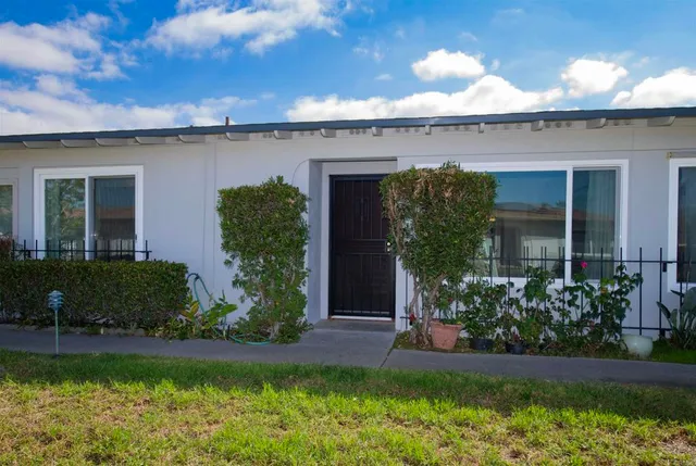 a view of a house with a yard and a large tree