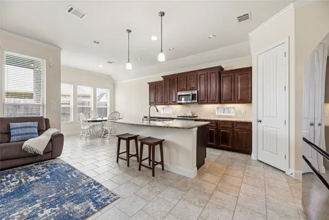 a kitchen with stainless steel appliances granite countertop a stove top oven a sink a dining table and chairs