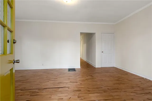 a view of an empty room with wooden floor and a window