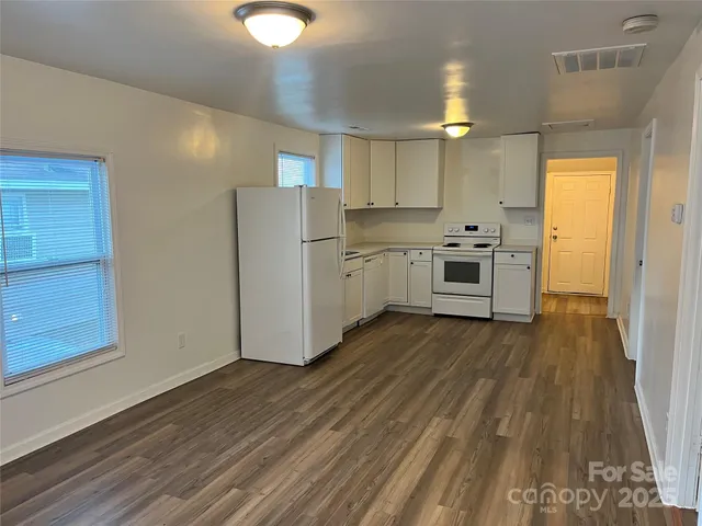 a kitchen with white cabinets and wooden floor