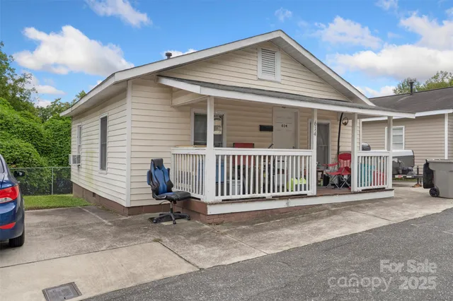 a view of a house with a small yard and large trees