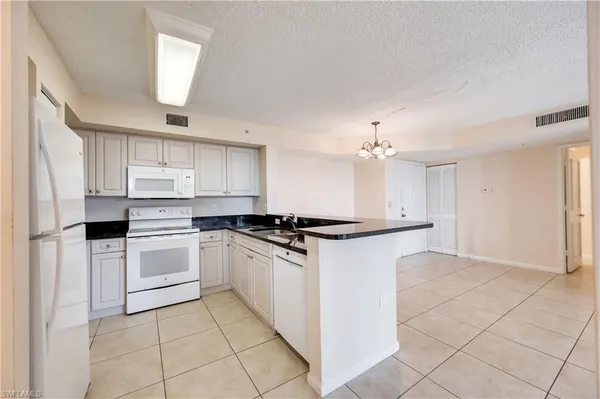 a kitchen with granite countertop white cabinets and white appliances