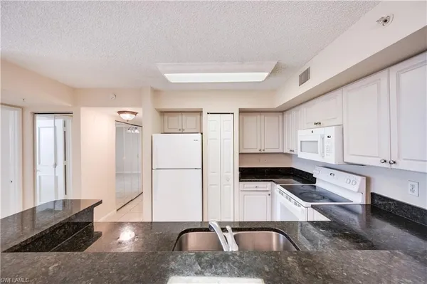 a kitchen with white cabinets and refrigerator