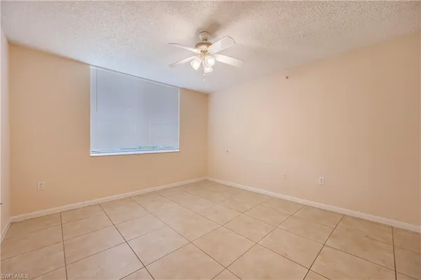 an empty room with a chandelier fan and windows