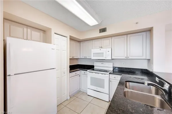 a kitchen with a refrigerator sink and cabinets